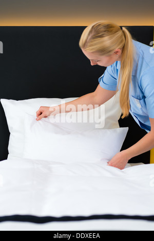 Room service - young chambermaid changing the bedding or bedclothes in a hotel room Stock Photo