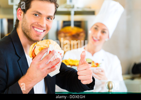 Doner kebab - friendly vendor and customer in a Turkish fast food eatery, with a freshly made pita bread Stock Photo