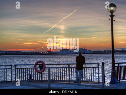 Man looking over to Birkenhead-Belfast Stena line ferry, from Albert Dock at Nighttime liverpool Merseyside England UK Stock Photo