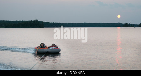 Tourists being pulled on an inflatable raft floating on water, Lake of The Woods, Keewatin, Ontario, Canada Stock Photo