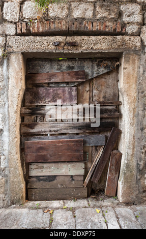 Old boarded up door in gray stone wall Stock Photo