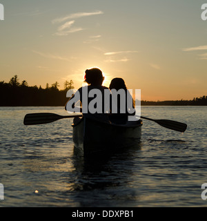 Woman rowing a boat with her daughter at sunset, Lake of The Woods, Keewatin, Ontario, Canada Stock Photo