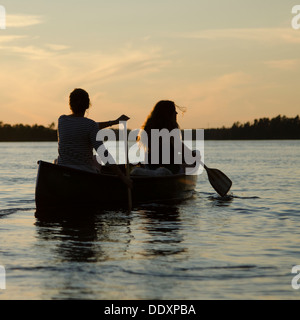 Woman rowing a boat with her daughter at sunset, Lake of The Woods, Keewatin, Ontario, Canada Stock Photo