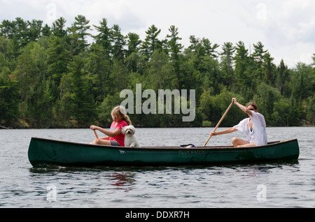 Woman rowing a boat with her daughter and Zuchon puppy, Lake of The Woods, Keewatin, Ontario, Canada Stock Photo