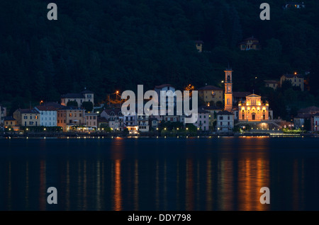 Village of Porto Ceresio with the Parish Church of Chiesa Sancto Ambrosio on Lake Lugano or Lago di Lugano at night Stock Photo