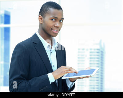 Young businessman, African-American, American, friendly, respectable, holding an iPad, standing in front of a skyline Stock Photo