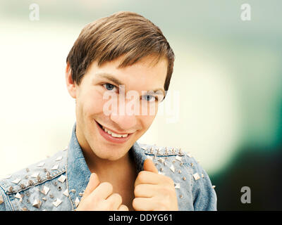 Smiling young man wearing a studded denim jacket, portrait Stock Photo