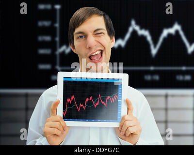 Winking businessman holding an iPad with a rising stock chart, symbolic image for economy, growth, economic recovery Stock Photo