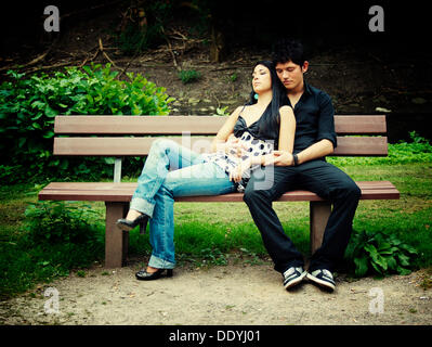 Young couple sitting on a park bench Stock Photo
