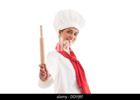 Portrait of female chef holding rolling pin isolated over white background Stock Photo