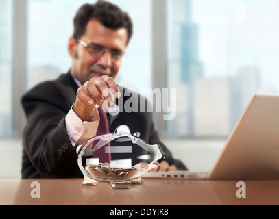 Businessman putting coin into piggy bank Stock Photo