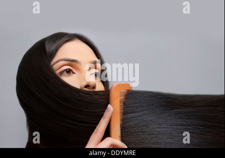 Young woman combing her beautiful long hair over colored background Stock Photo