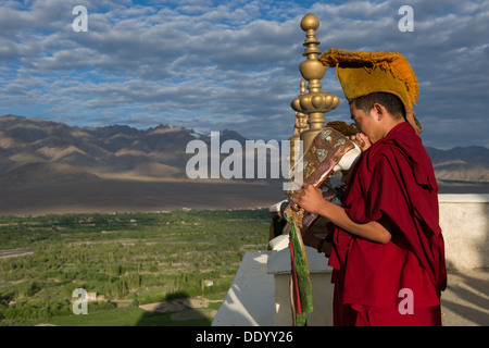 Monks blowing conch shells before morning prayers on the roof of Thiksey Gompa, Thiksey, (Ladakh) Jammu & Kashmir, India Stock Photo