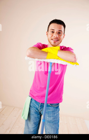 Smiling man leaning on a mop Stock Photo
