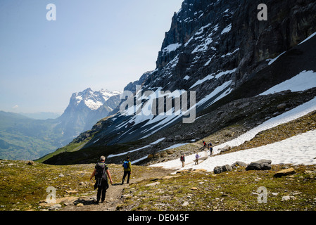 Hikers on the Eiger Trail near Grindelwald Switzerland. The trail runs directly below the North Face of the Eiger Stock Photo