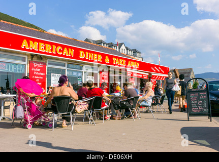 An American themed diner and take away with summer holiday visitors sitting at outside tables, busy colourful summer time scene Stock Photo