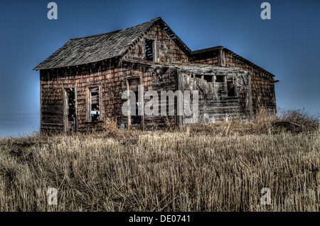 HDR photo of abandoned, old weathered, rustic rural house with porch and shed. Pioneer home falling apart Stock Photo