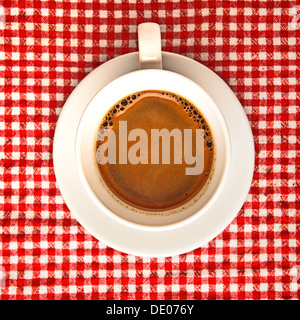 Coffee cup on table. Cup of domestic black coffee ob red and white checkered tablecloth background. Stock Photo