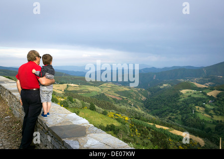 A grandfather and his grandson observe the landscape from the town of O Cebreiro in the Way of St. James in Galicia land. Stock Photo