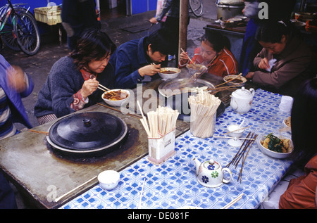 Chinese people eating out with chopsticks in a street market in China Stock Photo