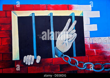 Chained hand making a peace sign, jail, graffiti at the East Side Gallery, Berlin Wall Stock Photo