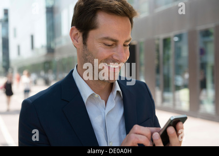 Businessman using smartphone outdoors Stock Photo