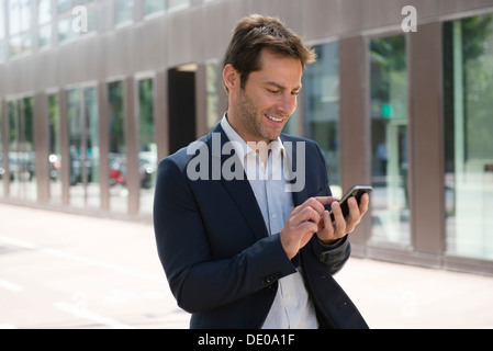 Businessman using smartphone outdoors Stock Photo