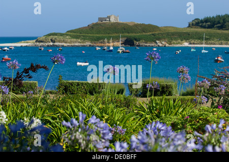 Looking across boats moored in Old Grimsby Quay to the Blockhouse, and Blockhouse Point, Tresco, Isles of Scilly, England Stock Photo