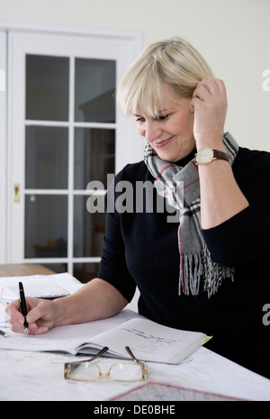 An architect sitting at her desk in her office and writing Stock Photo