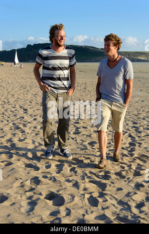 Two laughing young men are walking along the beach on the Atlantic coast, Bretagne, France, Europe Stock Photo