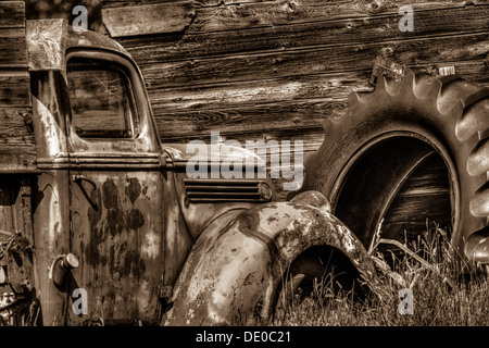 Rural setting of old rustic, antique, farm truck, sitting in front of an old barn or shed, Tractor tire in background. Stock Photo