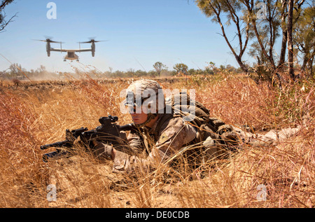 US Marine Corps Lance Cpl. John Ready provides security as an MV-22 Osprey tiltrotor aircraft takes off after inserting a platoon of Marines during an integrated live-fire exercise at the Bradshaw Field Training Area September 3, 2013 in the Northern Territory, Australia. Stock Photo