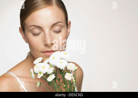 Young woman enjoying fragrence of bouquet of daisies Stock Photo