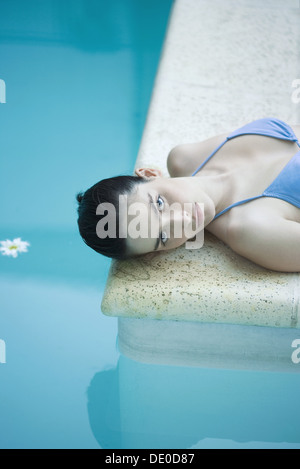 Woman lying on floor next to pool Stock Photo