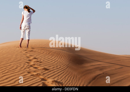 Girl ascending sand dune Stock Photo