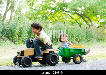 Young brother and sister riding on toy tractor