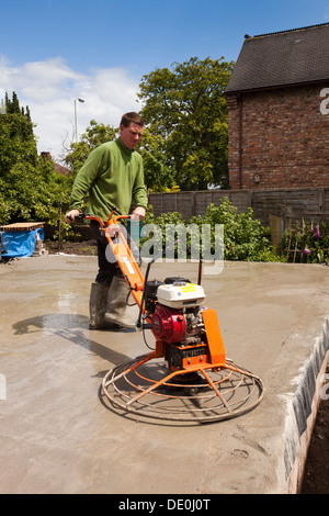 self building house, man using power float mechanical trowel to float finish readymixed concrete floor slab flat Stock Photo