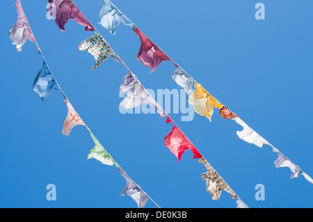 A group of colored shirts on a clothesline in front of blue sky Stock Photo