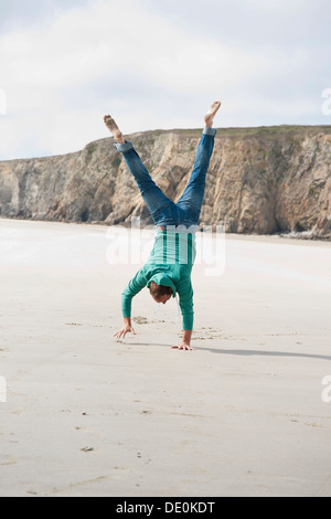 Man doing a handstand on the beach Stock Photo