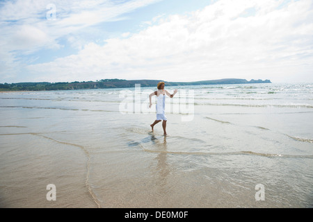 Woman running through small waves on a beach Stock Photo