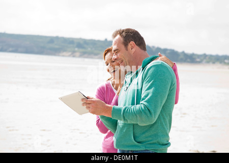 Couple playing with an iPad on a beach Stock Photo