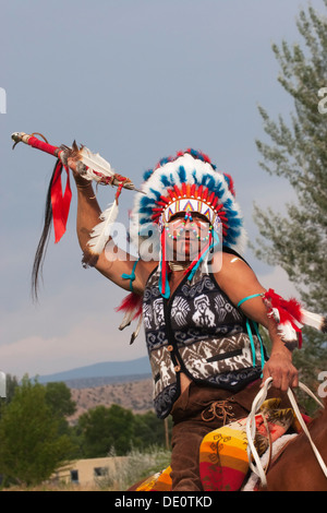 Warrior in Comanche clothing on horseback throwing spear Stock Photo