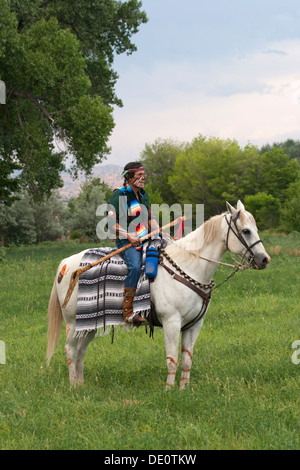 Warrior in Comanche clothing riding white horse Stock Photo