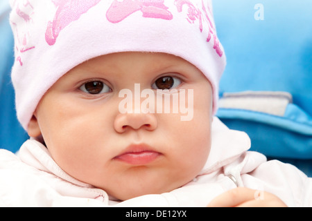 Brown eyed baby girl in pink hat, outdoor closeup portrait Stock Photo