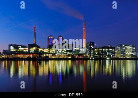 Illuminated Heizkraftwerk West, combined heat and power plant of Mainova AG, from the south bank of the Main river at dusk Stock Photo