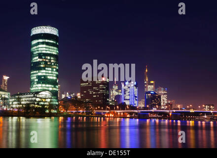 Skyline of Frankfurt with Westhafen Tower and Friedensbruecke bridge from the south-west bank of the Main river, at night Stock Photo