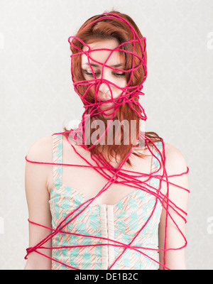 Conceptual image of woman trapped and constrained with red cotton yarn Stock Photo