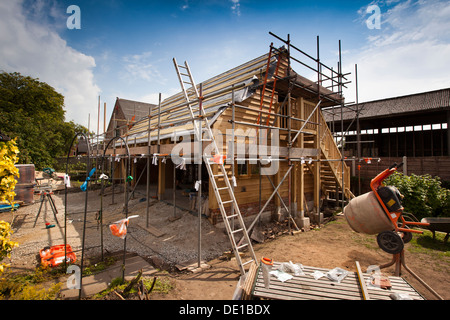 self building house, constructing green oak timber framed garage, external scaffolding around structure Stock Photo