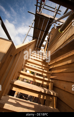 self building house, constructing green oak timber framed garage, external staircase and scaffolding around structure Stock Photo