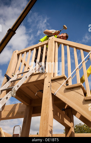 self building house, constructing green oak timber framed garage, pegging stair frame hammering in round dowel pegs Stock Photo